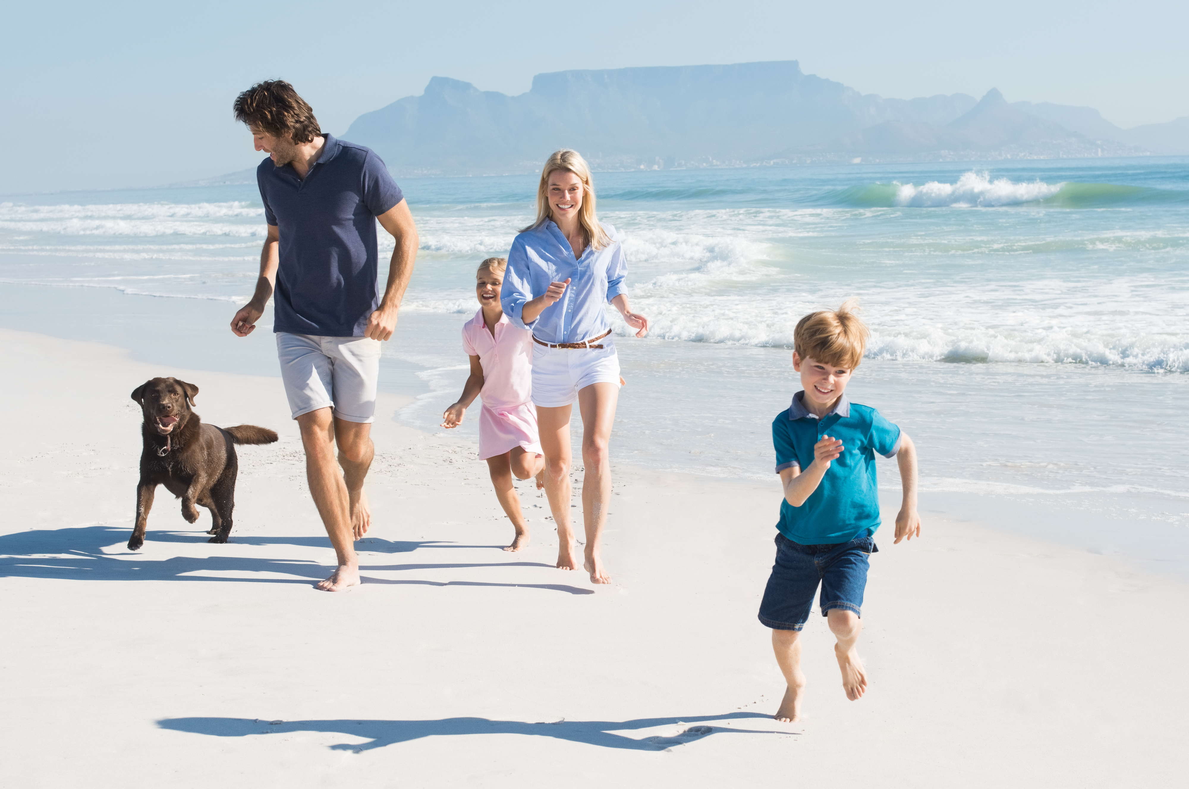 Glückliche Familie im Urlaub mit Hund am Strand