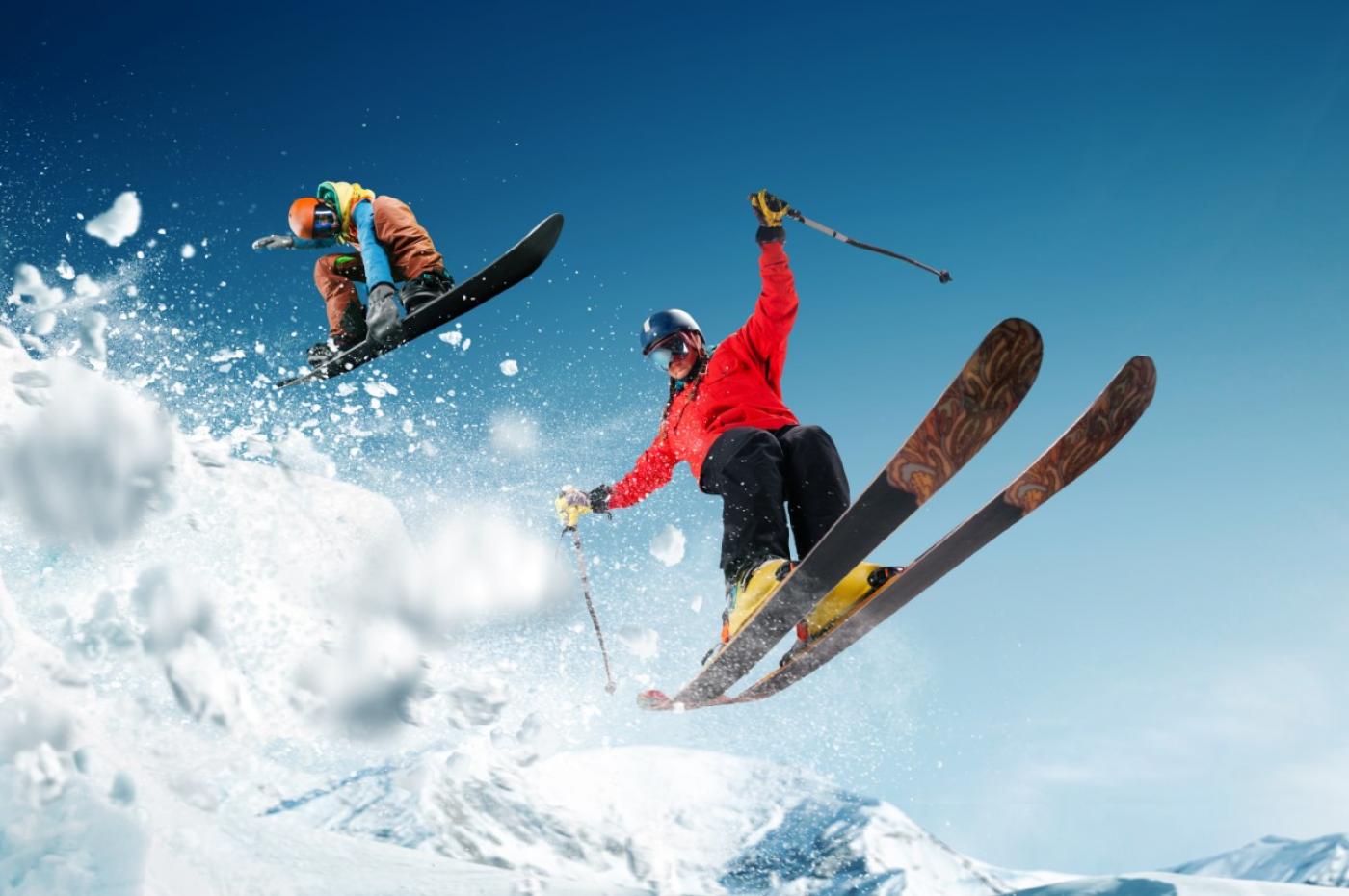 Springende Skifahrer haben Spass im Schnee im Winterurlaub